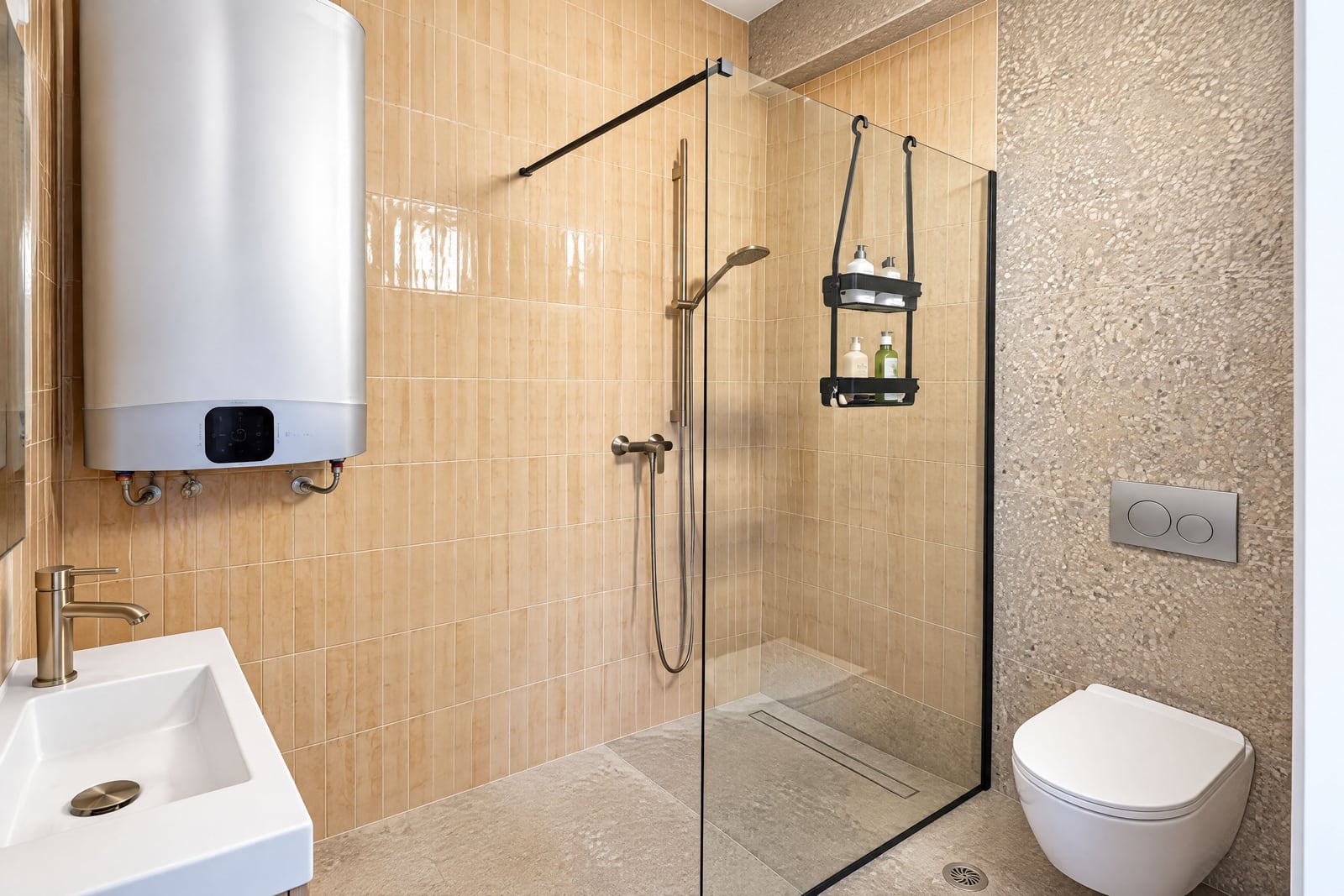 Bathroom featuring a glass shower enclosure, wall-mounted toilet, sink, and water heater against beige tiled walls.