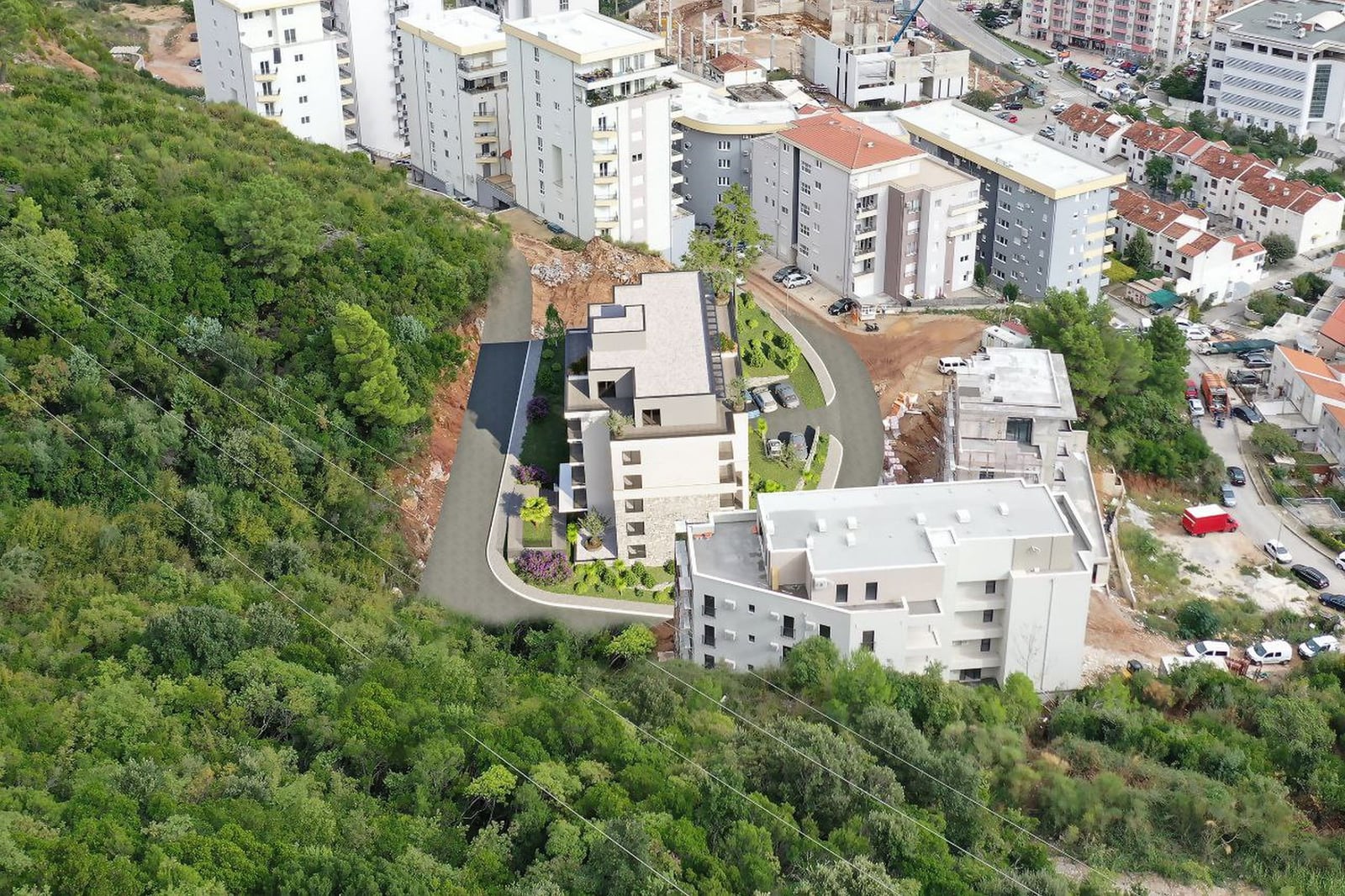 Aerial view of a residential complex in Budva, Montenegro: modern buildings, landscaped grounds, and a forested area.