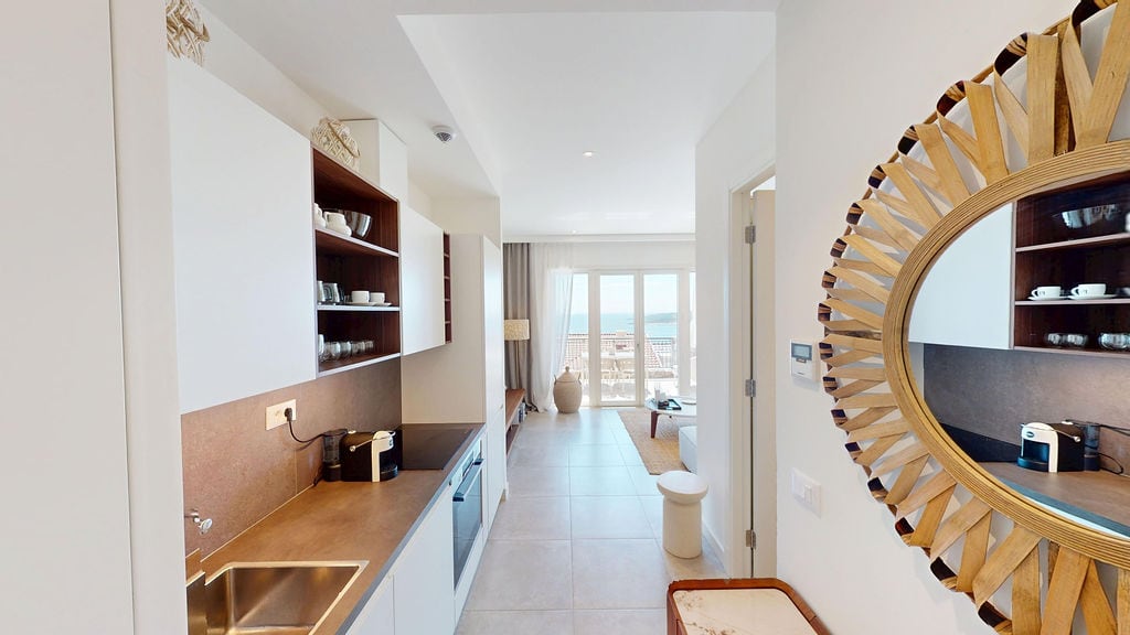 Modern kitchen in an apartment, Luštica, Montenegro: bright interior, built-in appliances, and a sea view from the living room.