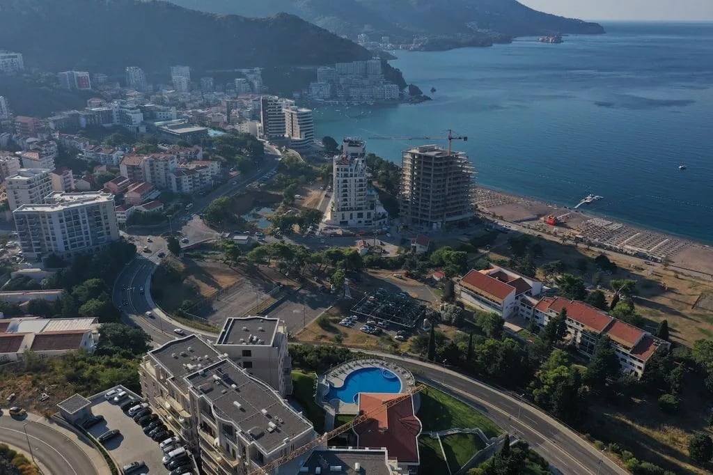 Aerial view of a residential complex with a swimming pool and the coast of the Bečići resort, Montenegro, panoramic view of the sea and mountains.