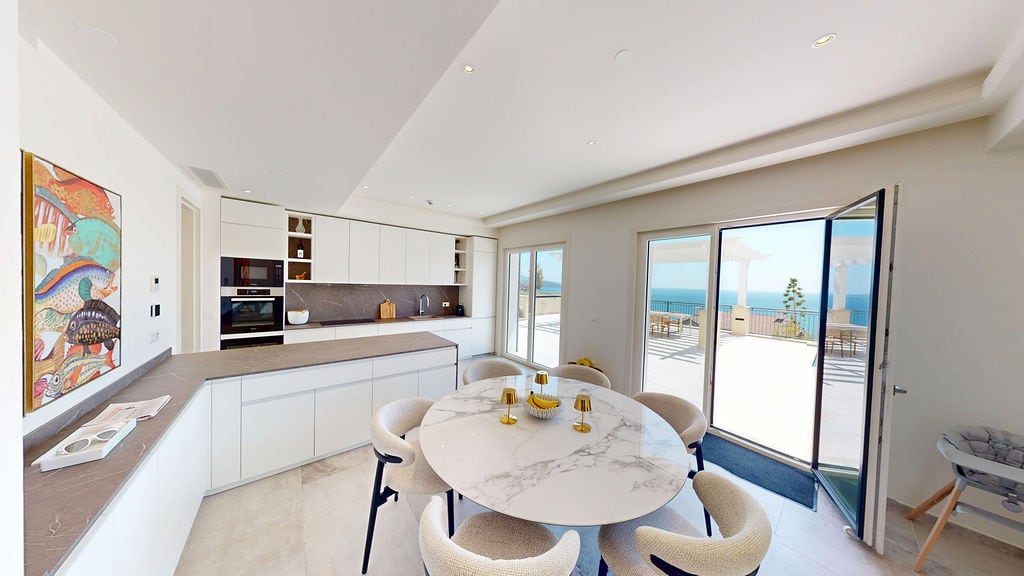 Modern kitchen-dining room with a marble table and sea view at a villa in Luštica, Montenegro.