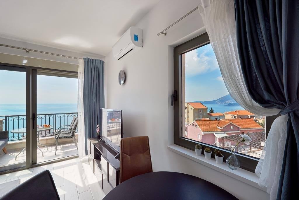 Living room with terrace access and sea view in an apartment, Pržno, Montenegro: modern interior, TV, and panoramic view.