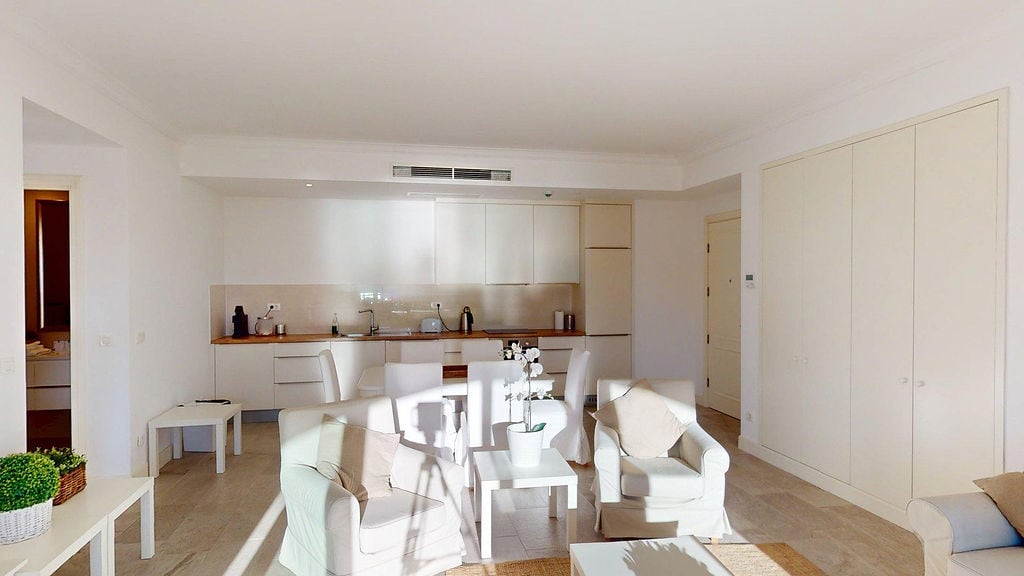 Bright living room with a modern-style kitchen in the Luštica apartments, Montenegro: white furniture and built-in wardrobes.
