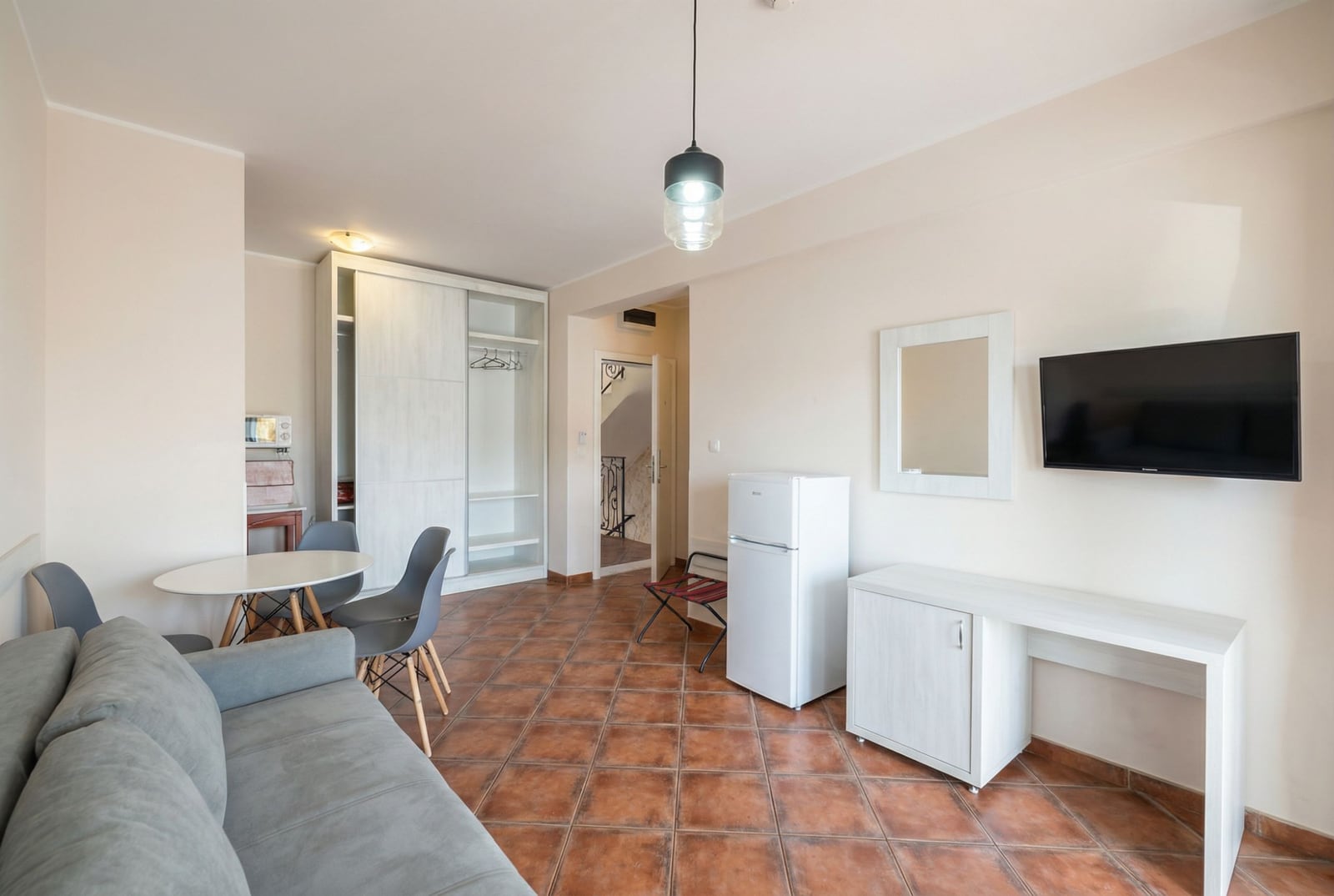 Living room interior in a hotel in Bečići, Montenegro: light-colored furniture, sofa, dining area and TV, tiled floor.