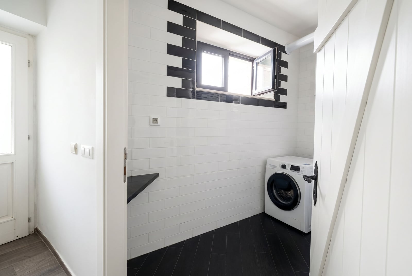 Bright laundry room with white tile and a washing machine in an apartment in Budva, Montenegro. Modern interior.