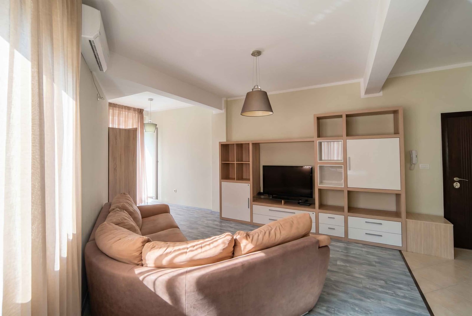 Bright living room with a beige sofa and furniture in an apartment in Becici, Montenegro: modern interior with a TV area.