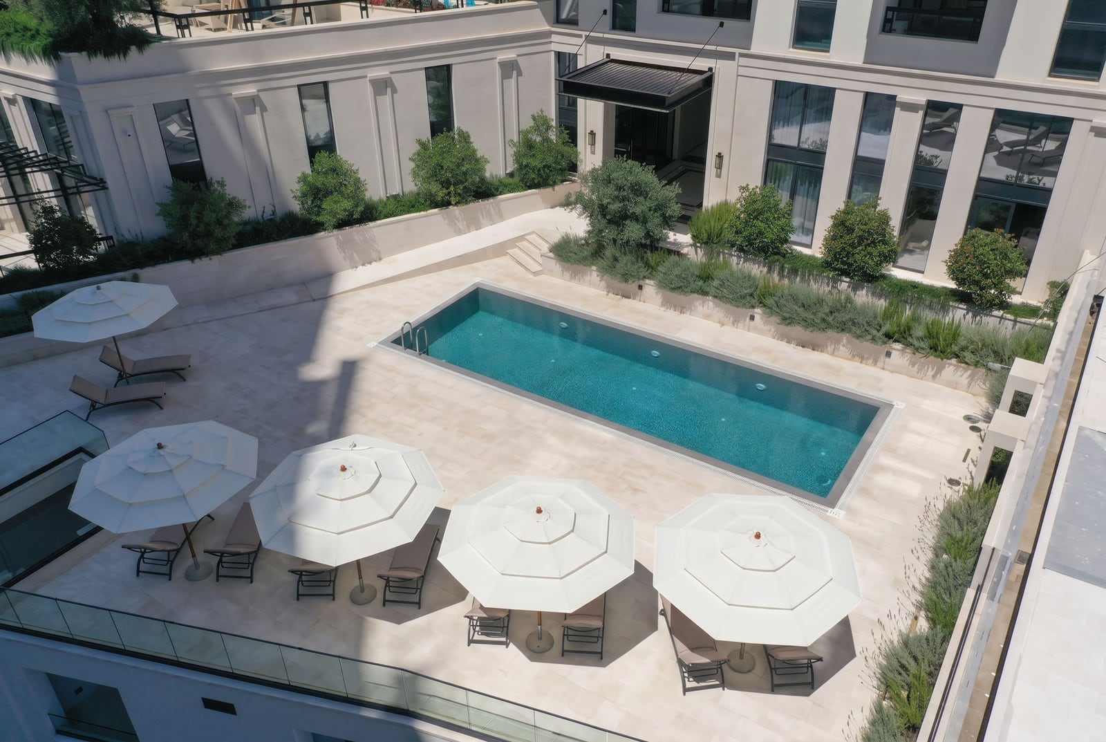 Outdoor swimming pool with sun loungers and umbrellas in the courtyard of a luxury residential complex in Bečići, Montenegro.