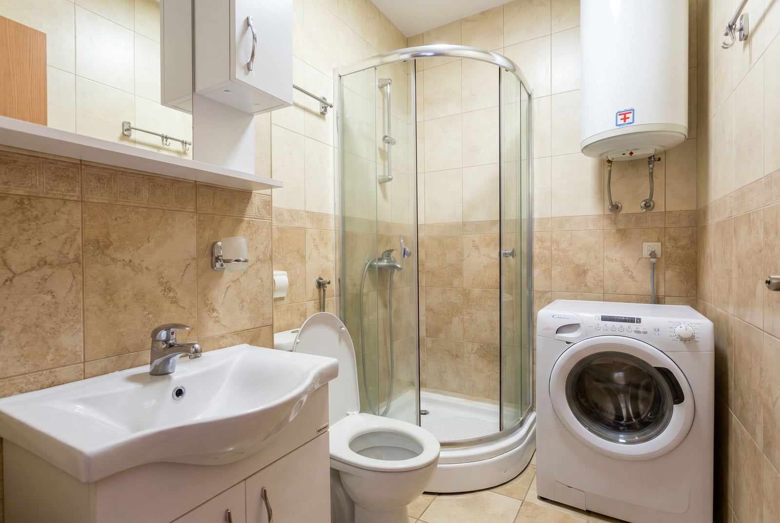 Bathroom in an apartment in Budva, Montenegro: shower cabin, washing machine, water heater, and tile finish.