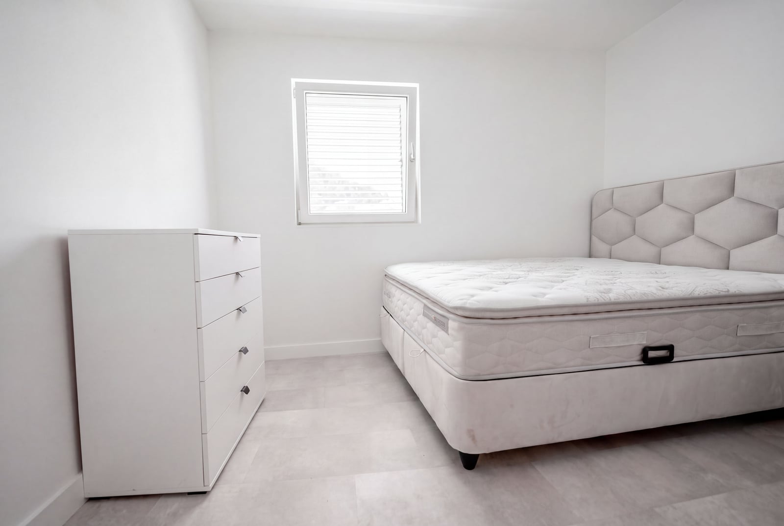 Bright bedroom with a double bed and dresser in an apartment, Sveti Stefan, Montenegro. Modern interior.