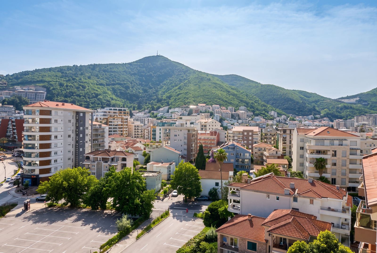 Panoramic view of residential buildings, green mountain, and urban development in Budva, Montenegro