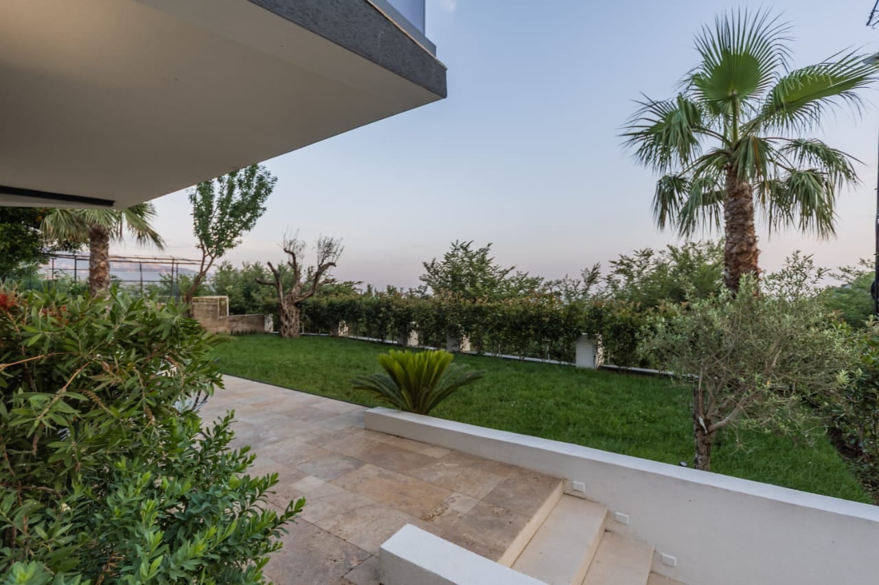 Well-maintained garden with palm trees and villa terrace in Budva, Montenegro: view of the private area and landscape design.