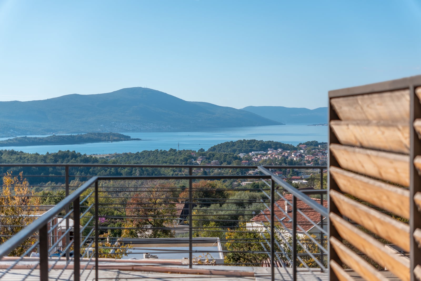 View from the townhouse balcony in Kavač, Montenegro: panoramic view of the Bay of Kotor, mountains, and the surrounding green landscape.