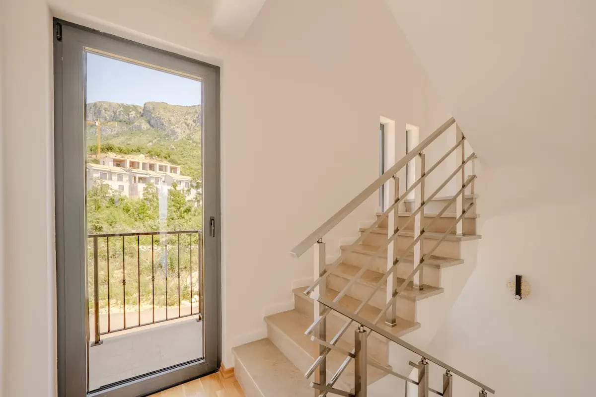 Staircase with metal railings and a panoramic window with a mountain view in a villa, Reževići, Montenegro.