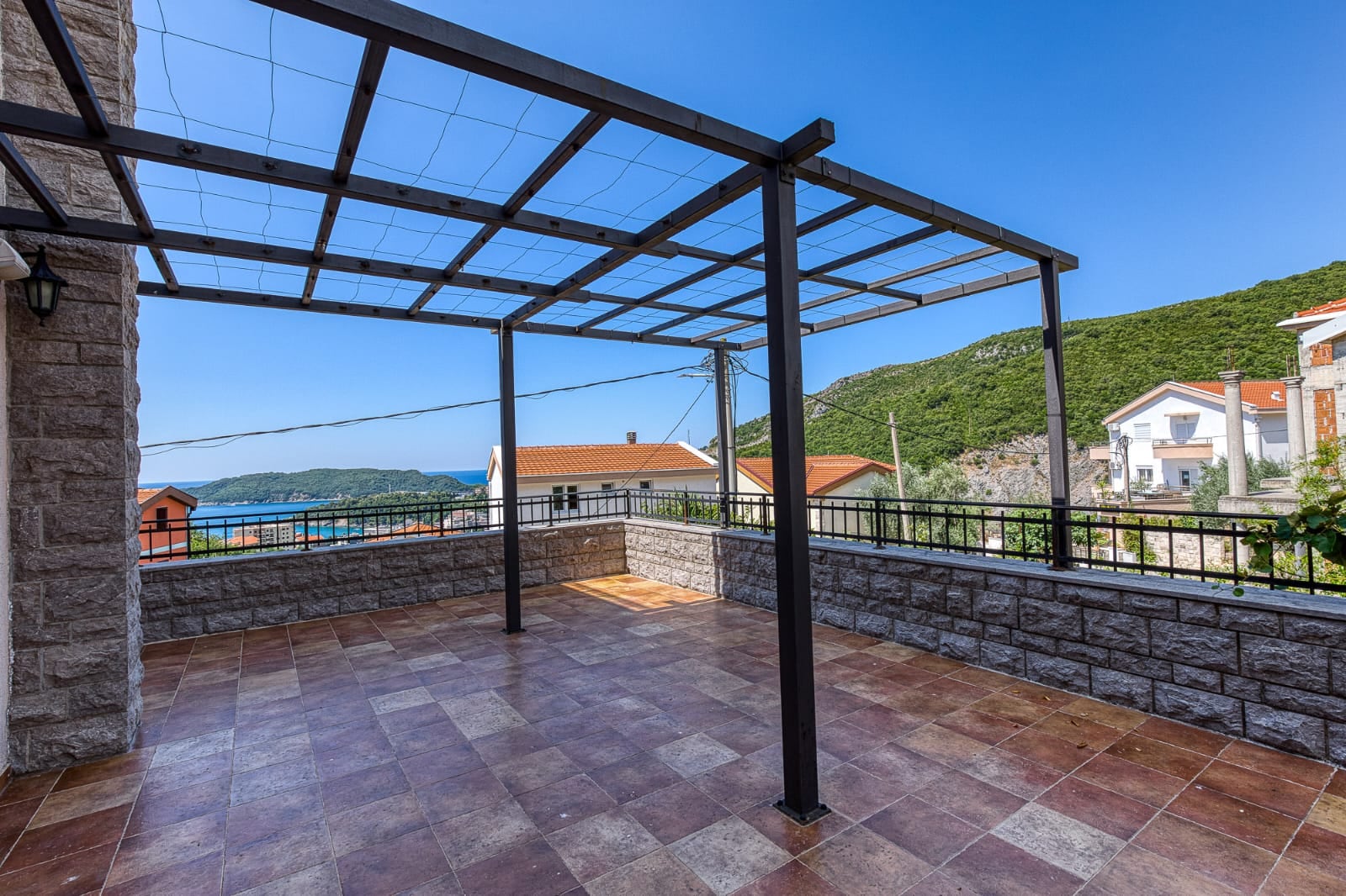 Spacious terrace with a pergola and sea view at a villa in Becici, Montenegro. Stone finishes and tiled flooring.