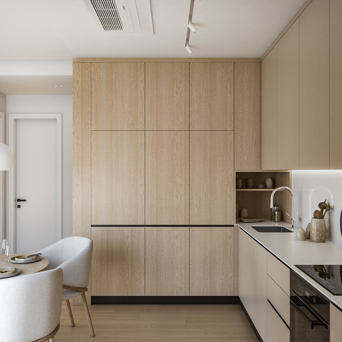 Modern kitchen featuring light wood cabinetry, a sink, cooktop, and a partial view of a dining area with upholstered chairs.