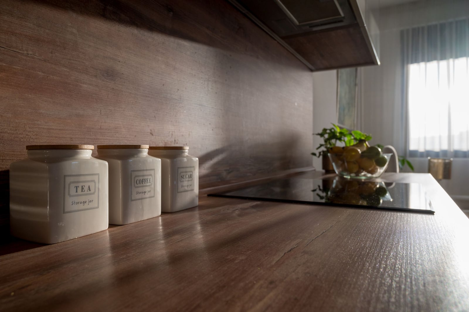 Modern kitchen in an apartment in Tivat, Montenegro: wooden countertop, ceramic jars, and a cooktop.