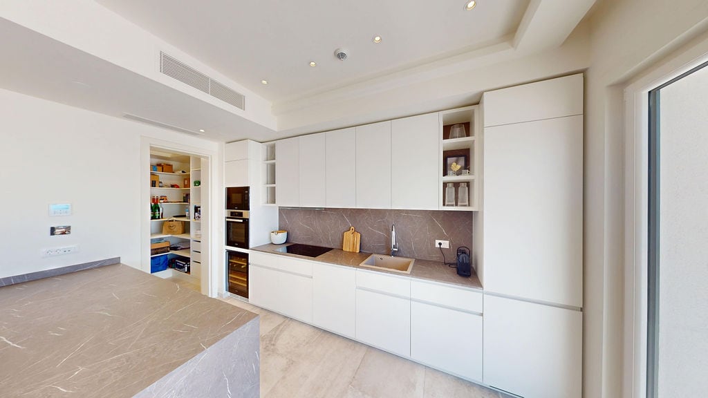 Modern white kitchen with an island and pantry in a luxury villa, Luštica, Montenegro: stylish interior and appliances.