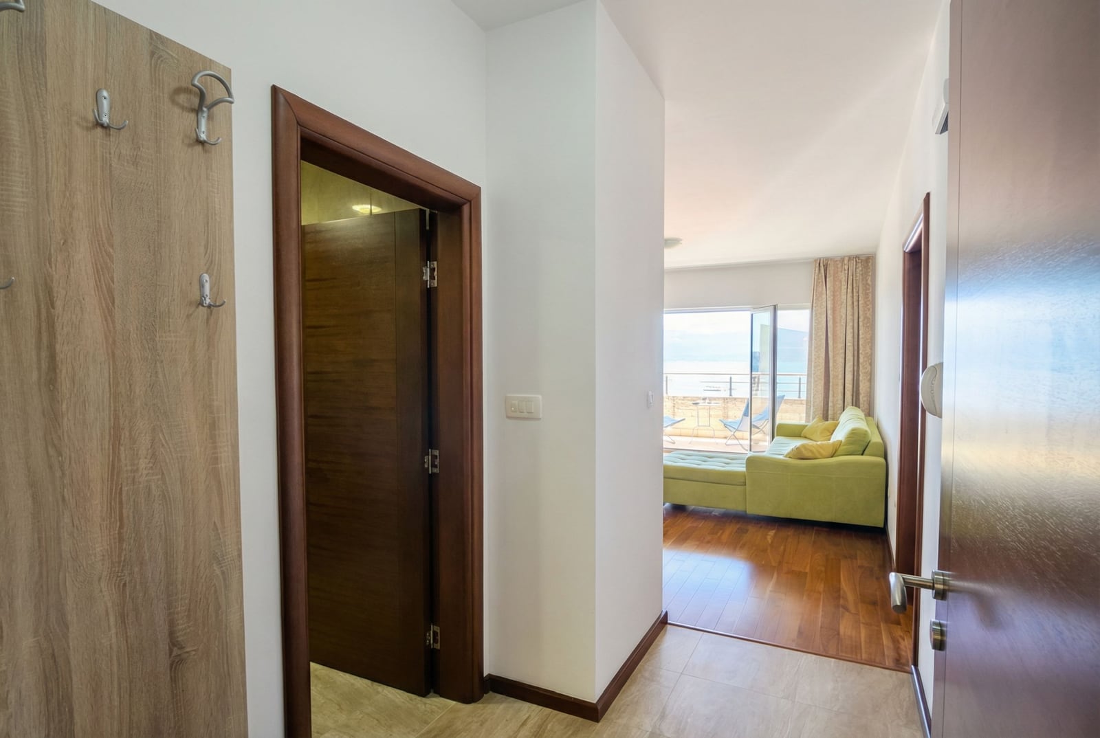 Hallway and view of the living room with terrace and sea in an apartment in Tivat, Montenegro: modern interior, parquet.