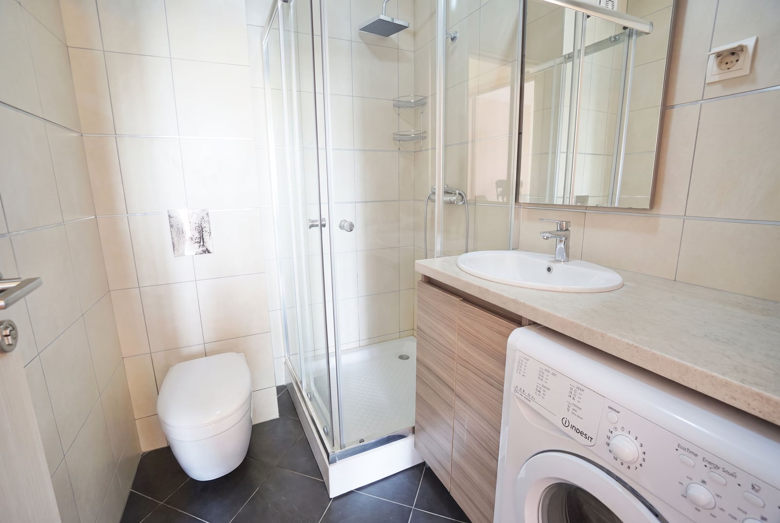 Modern bathroom with a shower cabin, sink, toilet, and washing machine in an apartment in Budva, Montenegro.