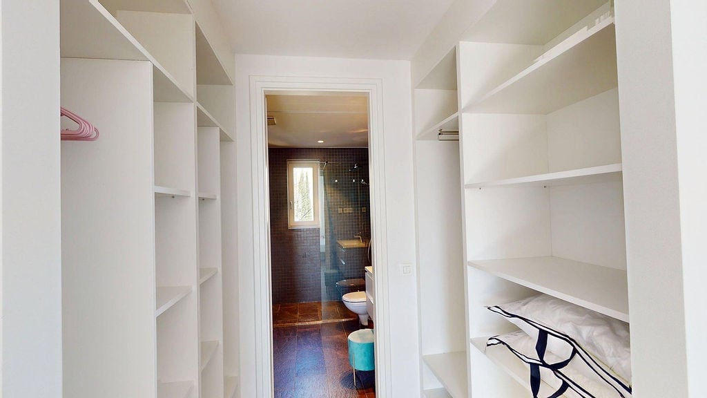Spacious dressing room with white shelving and a passage to the bathroom in an apartment, Luštica, Montenegro.