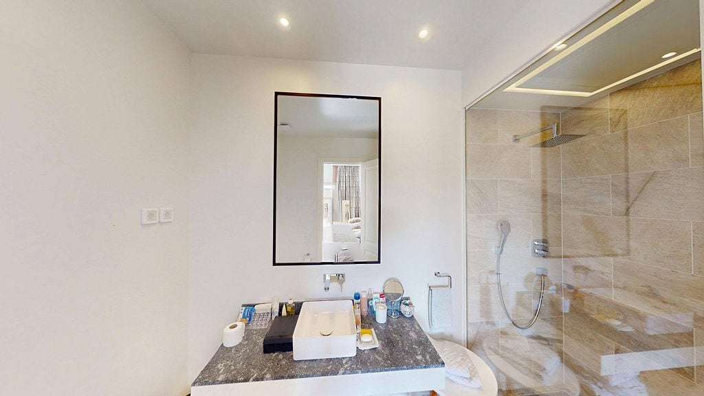 Modern bathroom in an apartment, Luštica, Montenegro: stone countertop, shower cabin, and stylish mirror.