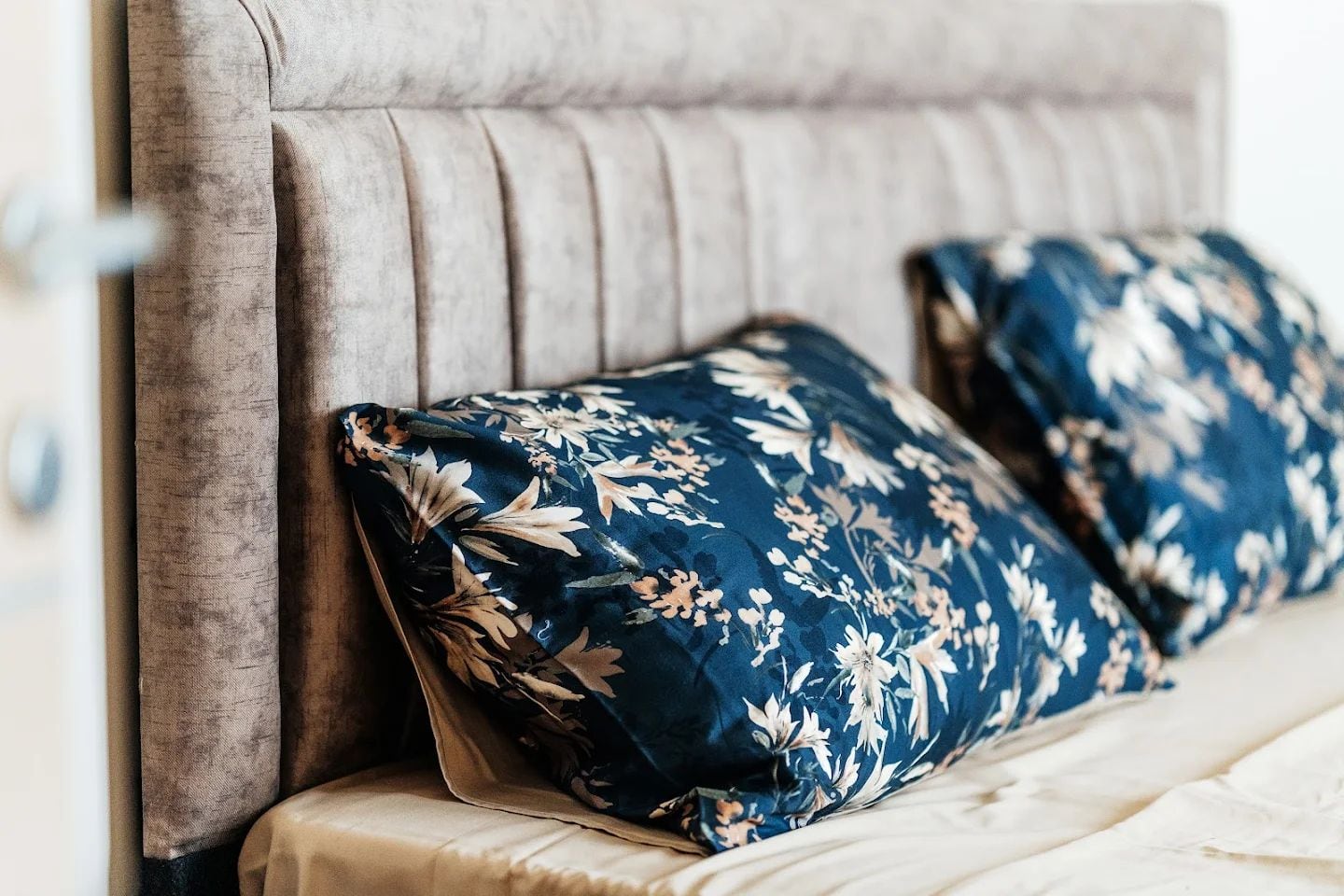 Soft upholstered headboard of a double bed with blue pillows in an apartment interior in Budva, Montenegro.