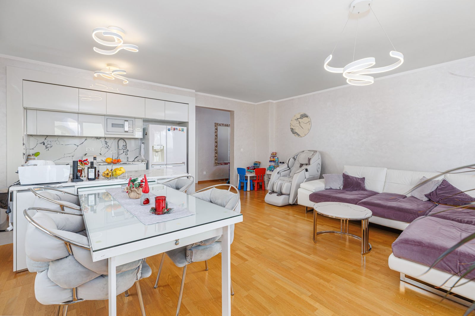 Modern living room with kitchen in a penthouse, Becici, Montenegro: white furniture, purple sofa, and dining area.