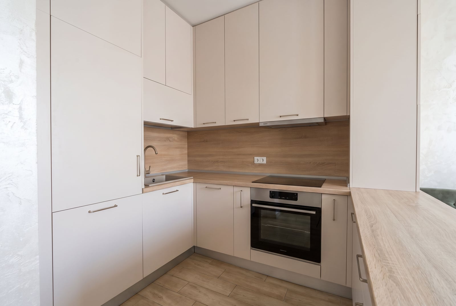 Modern kitchen with white cabinets, wood countertops, built-in oven, sink, and induction cooktop.