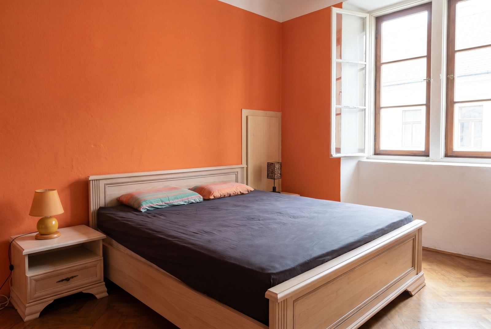 Bedroom with a double bed and orange walls in a house for sale, Dobrota, Montenegro.