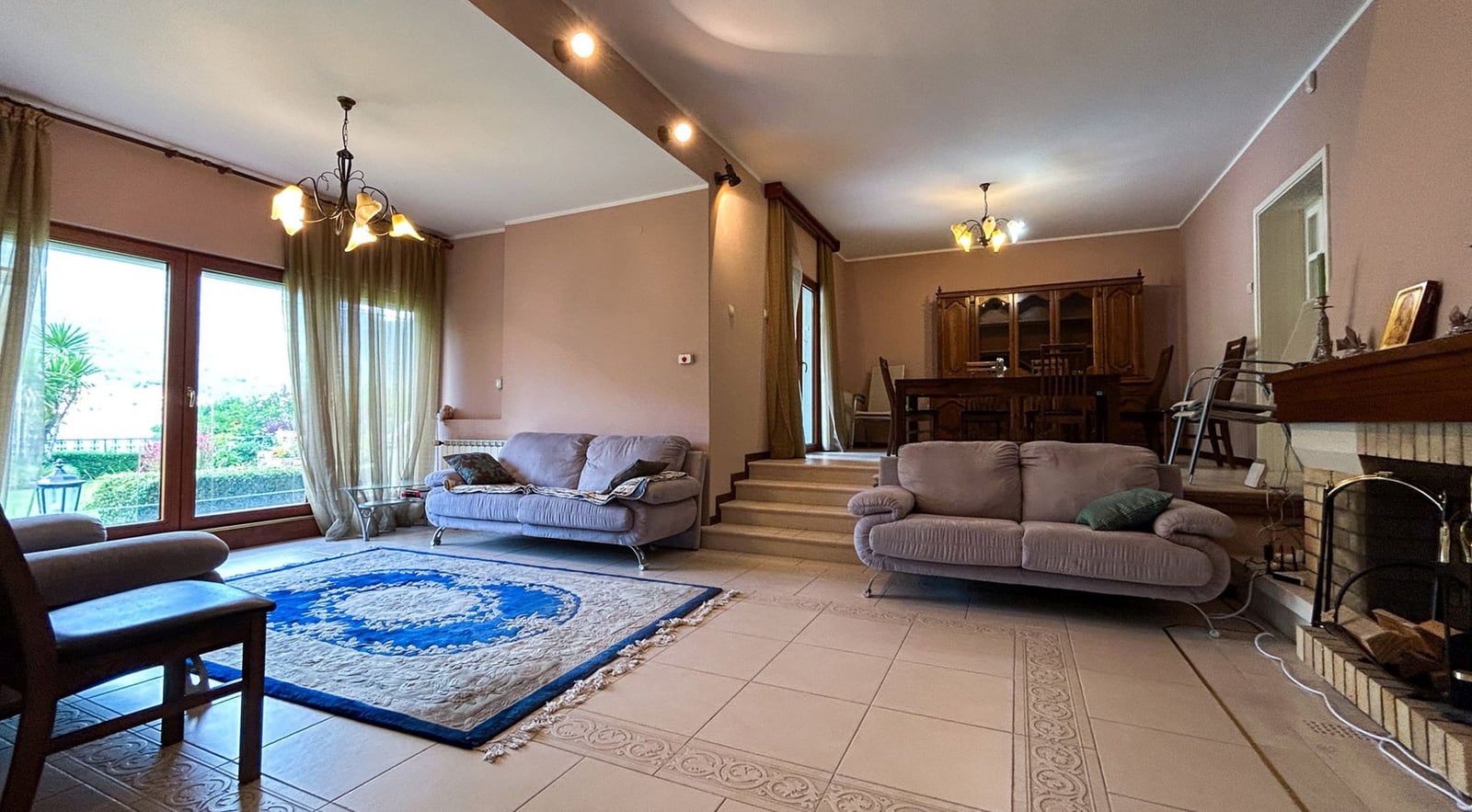 Spacious living room with a fireplace and soft seating in a villa in Dobrota, Montenegro: view of the dining area and terrace.