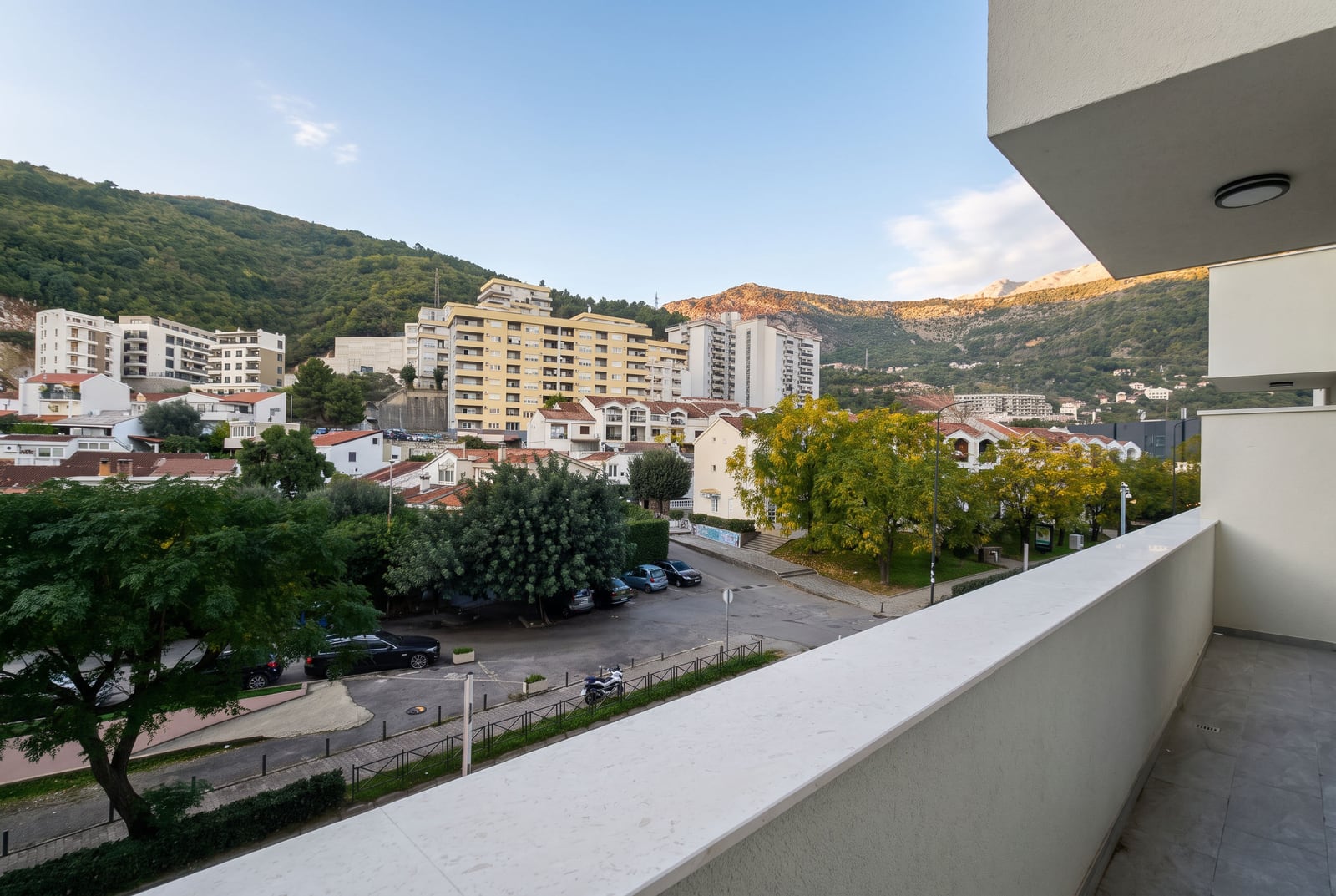 View from the apartment balcony in Budva overlooking the city, green hills, and mountains in Montenegro.