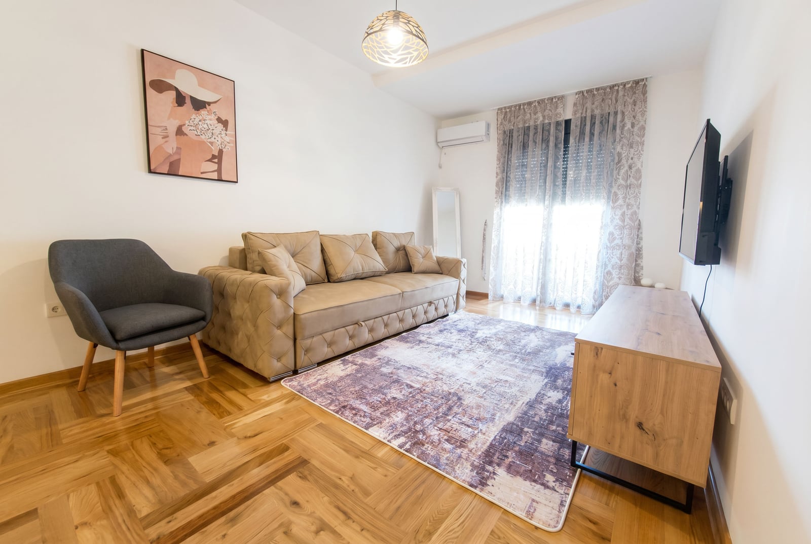Cozy living room with a beige sofa, armchair, and parquet flooring in an apartment in Rafailovici, Montenegro. Modern interior.