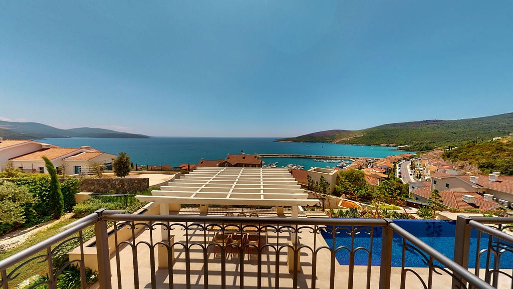 View from the balcony of a villa in Luštica, Montenegro: terrace with pergola, swimming pool, and panoramic view of the Adriatic Sea and marina.