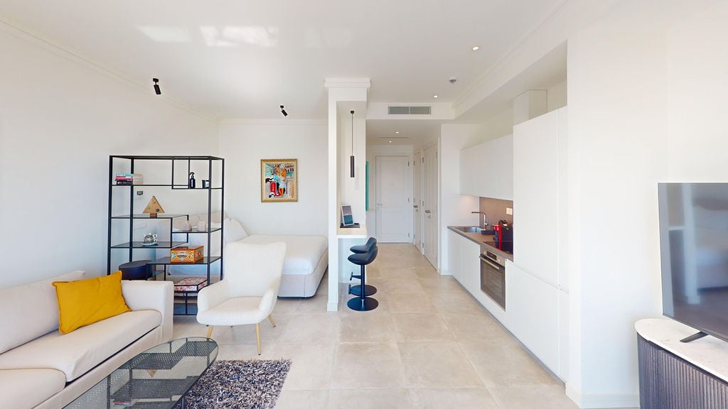 Modern living room with kitchen in Lustica apartments, Montenegro: bright interior, upholstered furniture, and dining area.