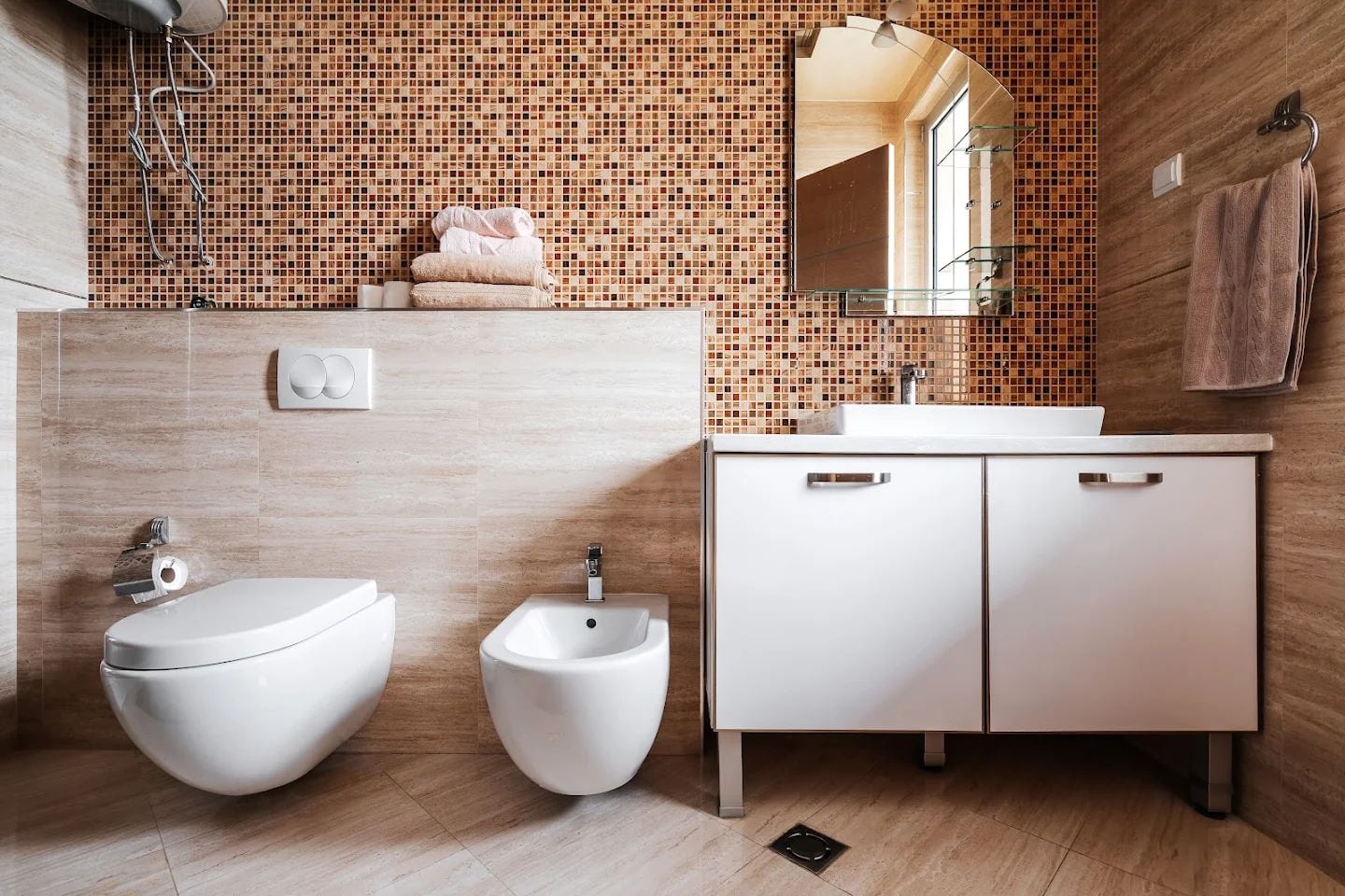Modern bathroom in an apartment in Budva, Montenegro: wall-mounted fixtures, mosaic tile, and a white vanity with sink.