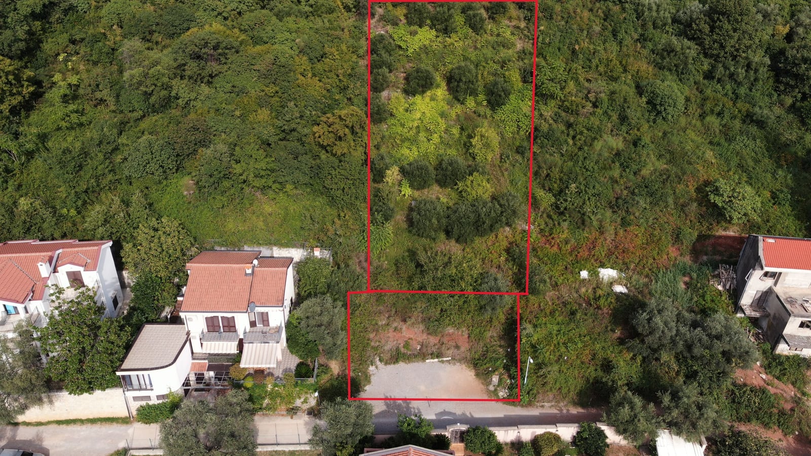 Building plot in Budva, Montenegro: aerial view of the land with trees and an access road.