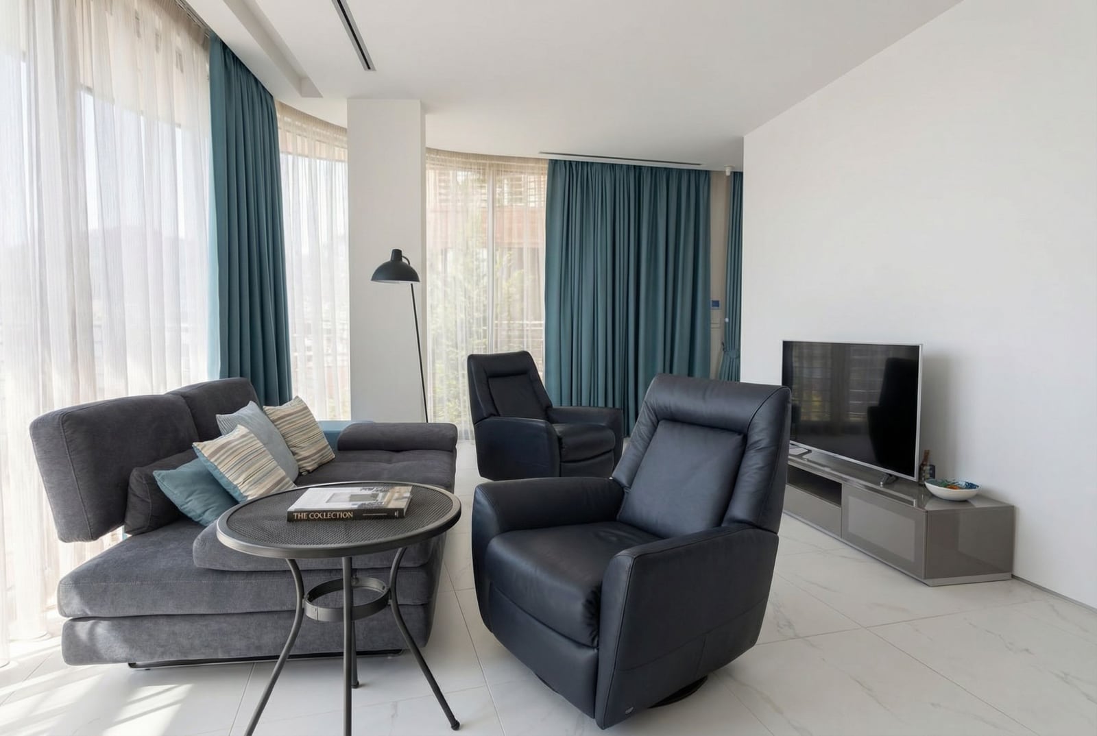 Modern living room in Dukley, Budva, Montenegro: leather armchairs, gray sofa, panoramic windows, and a bright interior.