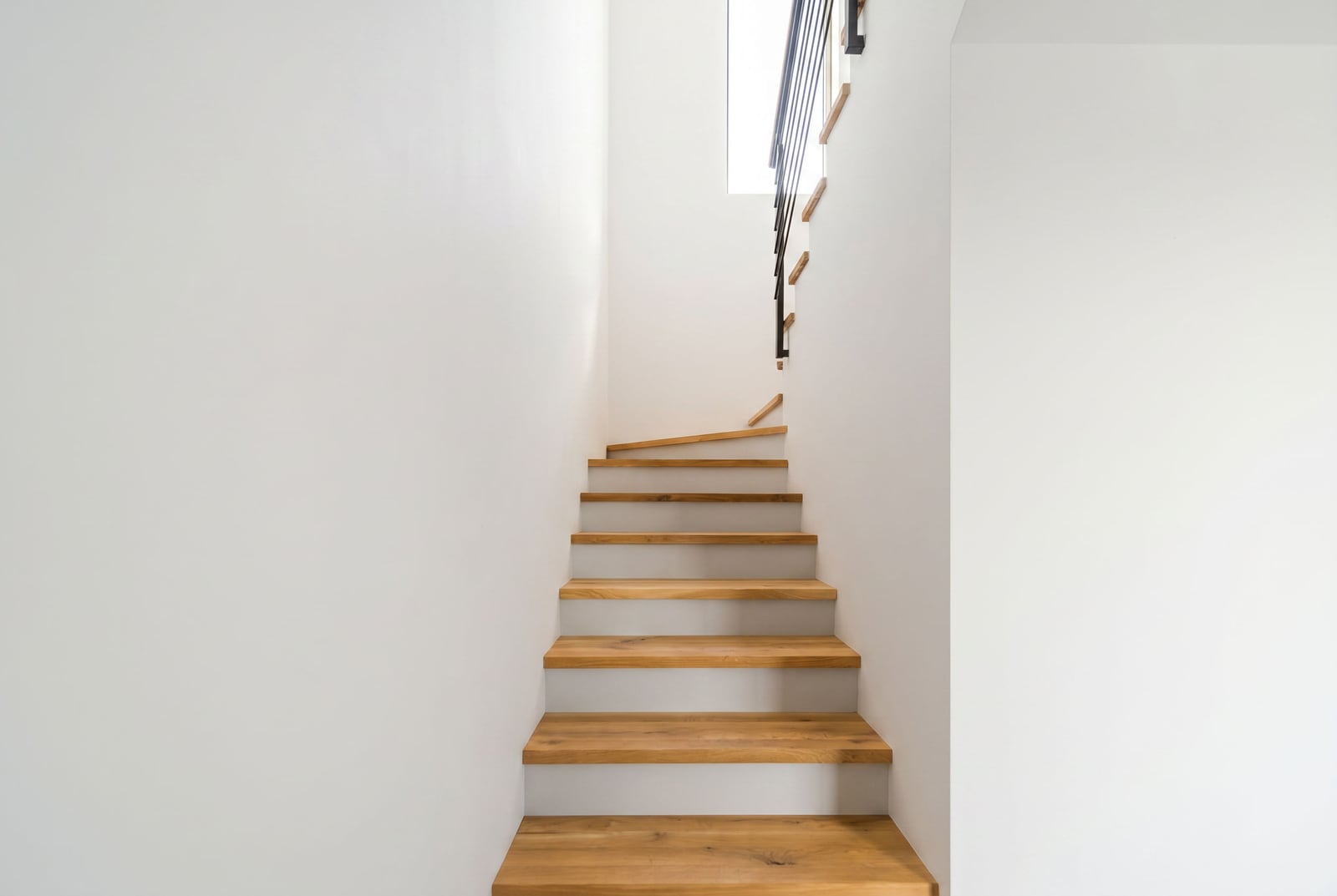 Modern wooden staircase in a townhouse in Kavač, Montenegro, with white walls and stylish railings.