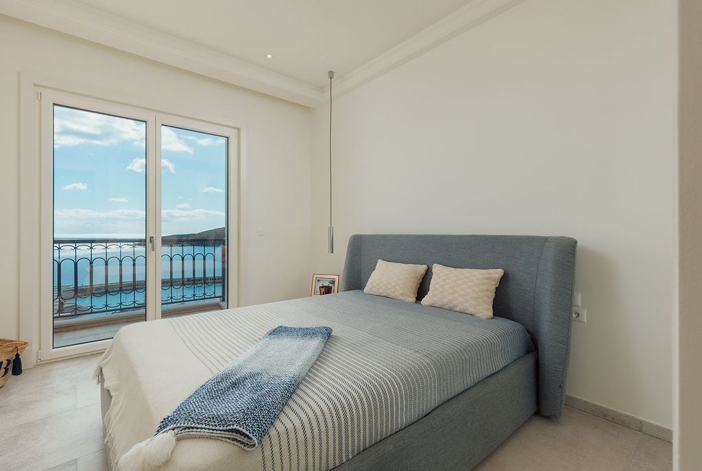 Modern bedroom with a double bed and panoramic sea view in a residential complex, Luštica, Montenegro.