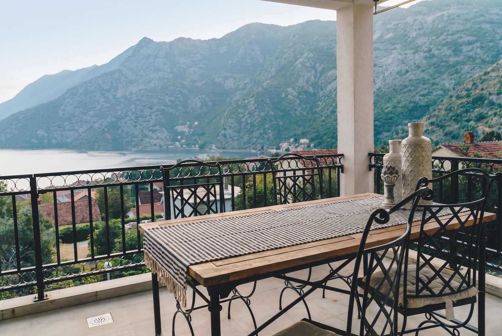 Terrace with wrought iron furniture and panoramic views of the Bay of Kotor and mountains in Risan, Montenegro.
