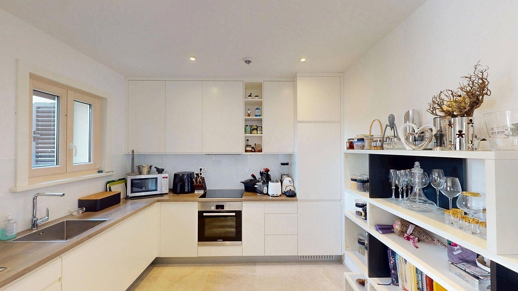 Modern white kitchen with appliances in an apartment, Lustica Bay, Montenegro: built-in cabinets, shelving unit, and light interior.