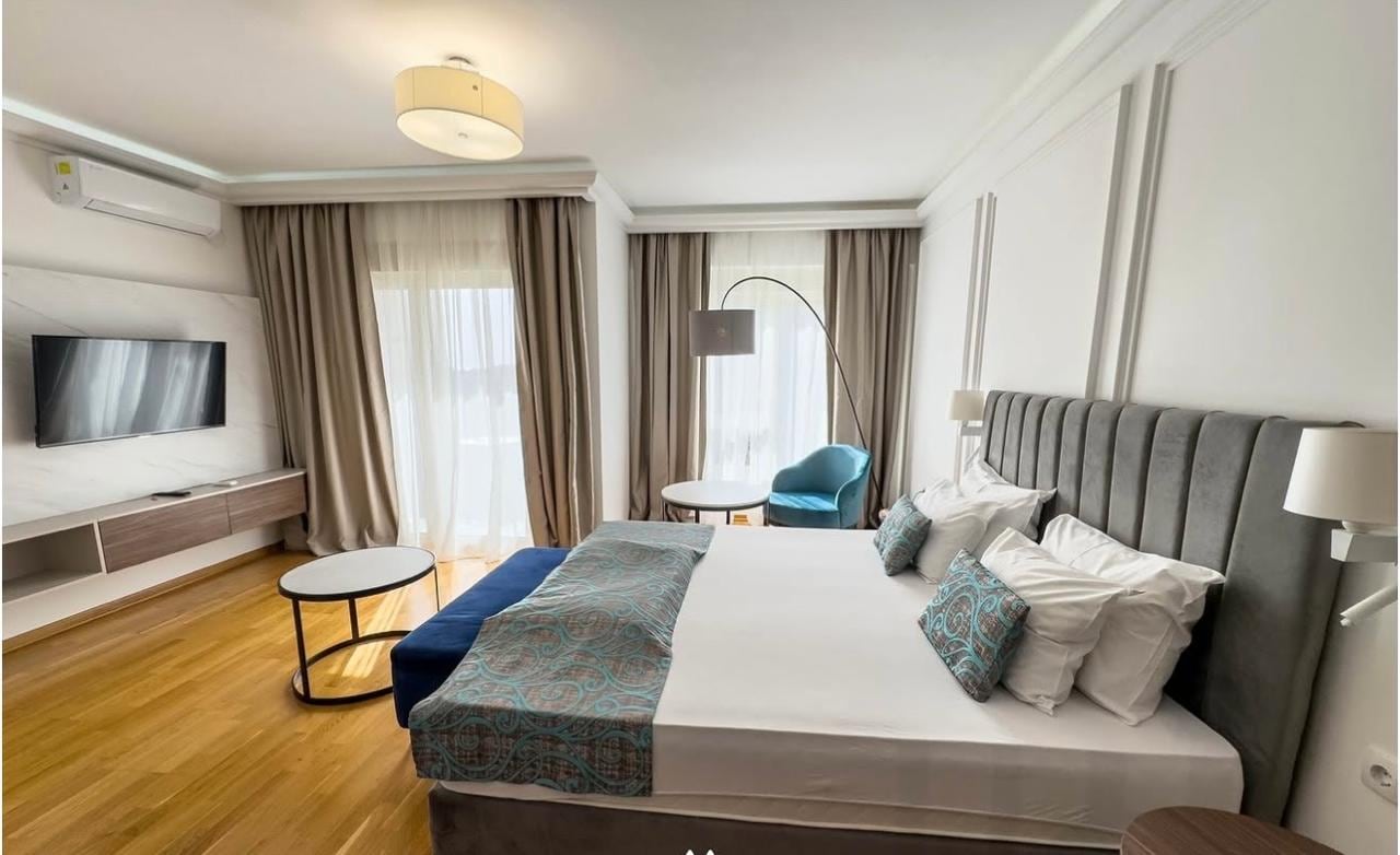 Modern bedroom in an apartment in Bečići, Montenegro: double bed, panoramic windows, parquet flooring, and stylish decor.