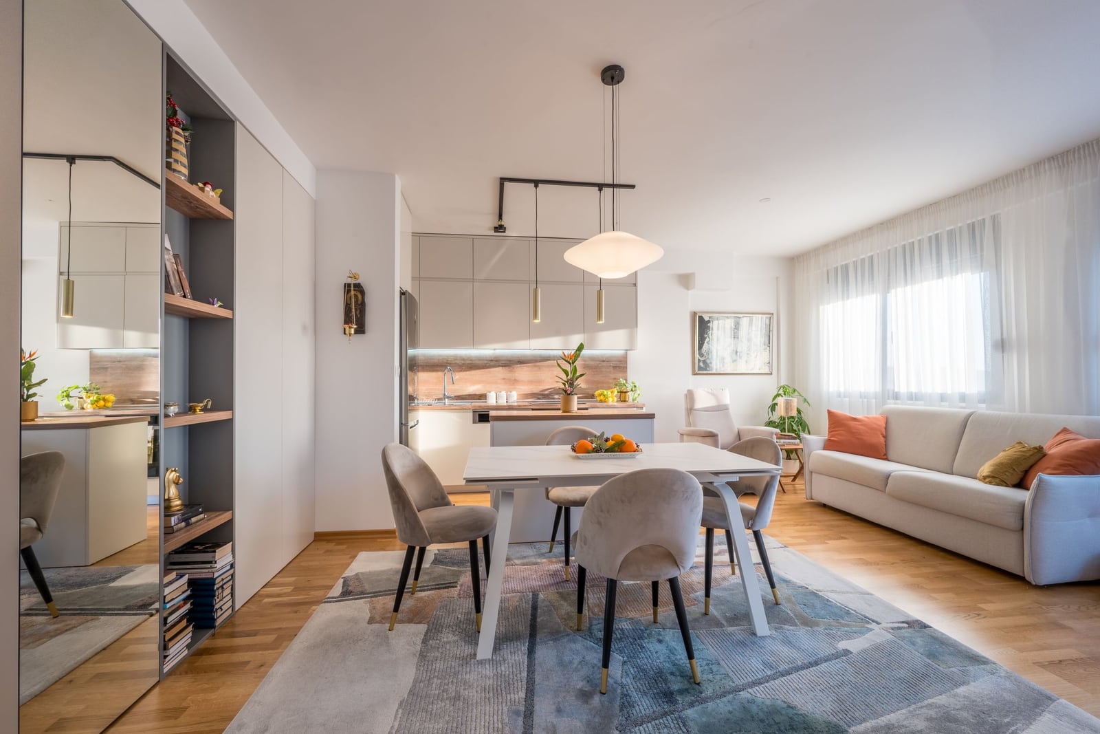 Modern living room with a kitchen in an apartment in Tivat, Montenegro: dining area, light-colored furniture, and stylish interior.