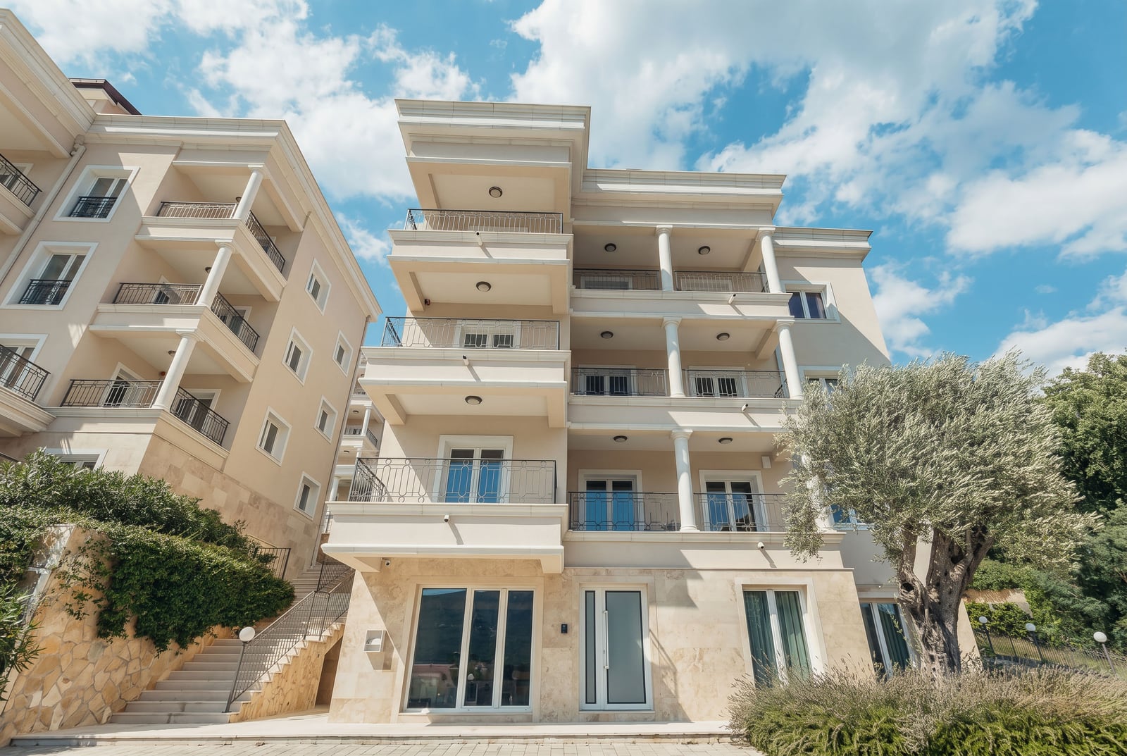 Modern residential complex with terraces in Kumbor, Montenegro: building facade with stone and olive tree finishes.