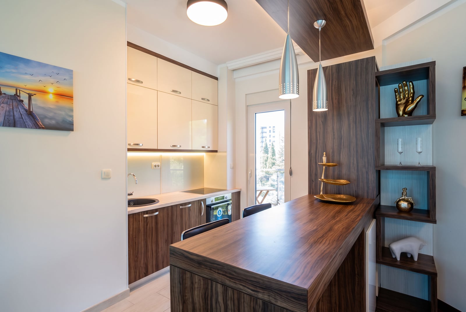 Modern kitchen featuring a dark wood breakfast bar, white upper cabinets, and pendant lighting.
