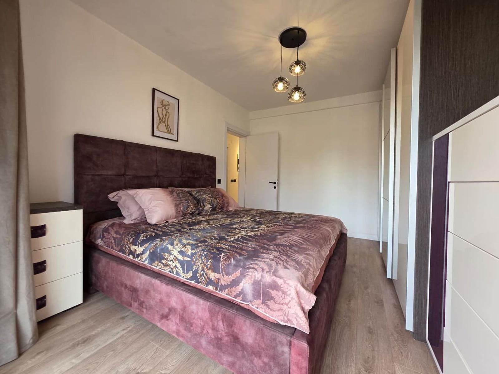 Modern bedroom in an apartment in Bečići, Montenegro: a double bed with a soft headboard, wardrobe, and stylish decor.