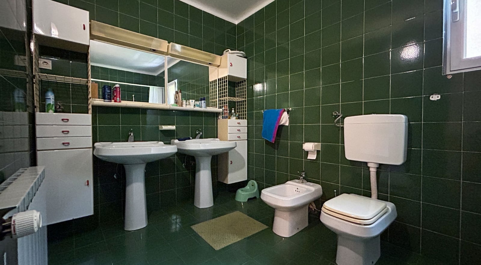 Bathroom with green tiles, two sinks, and a bidet in a villa in Dobrota, Montenegro.