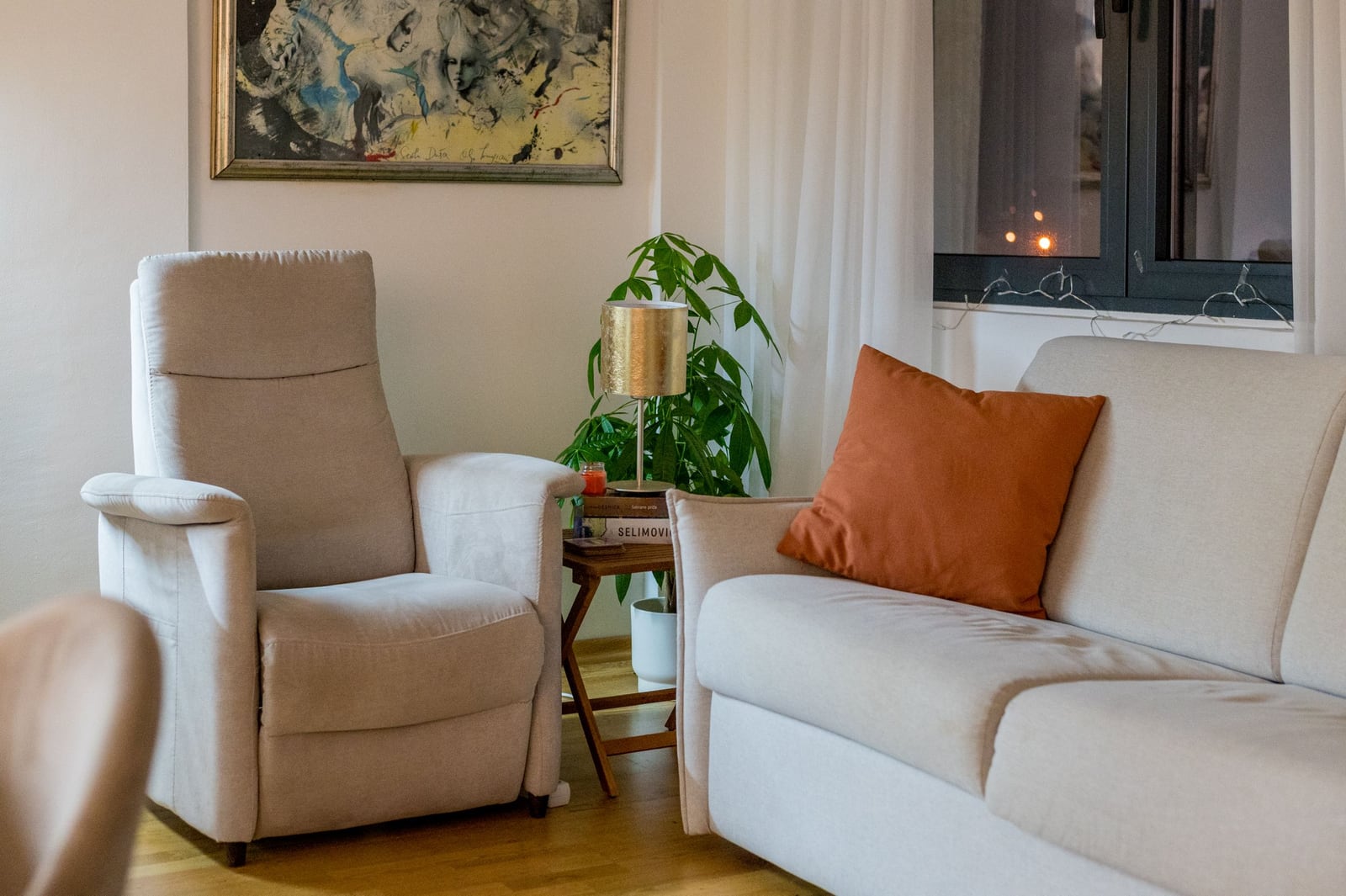 Cozy living room in a Tivat apartment, Montenegro: light-colored sofa, armchair, coffee table, and interior decor.