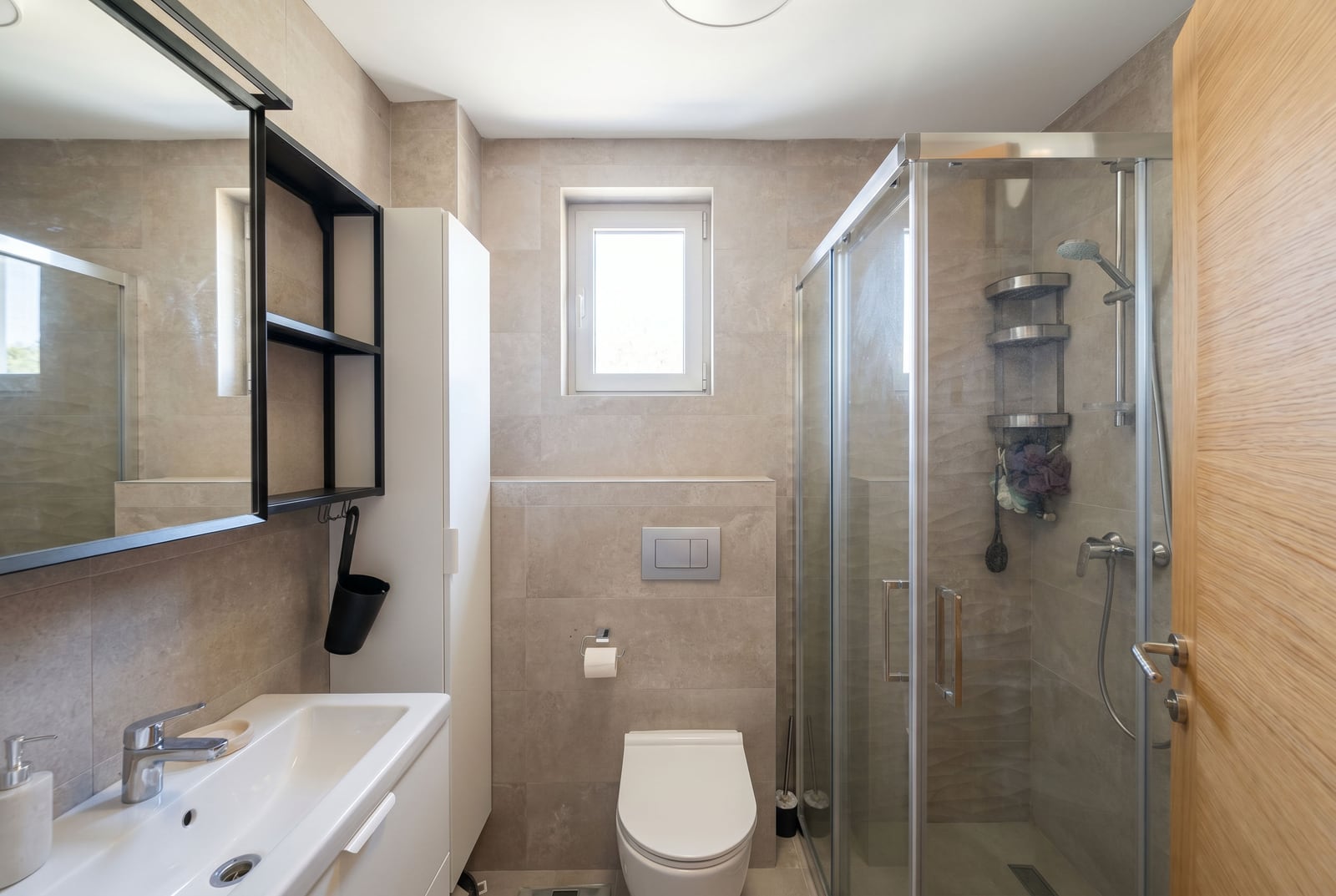 Modern bathroom with a walk-in shower in an apartment in Bečići, Montenegro: white sanitary ware and beige tiles.