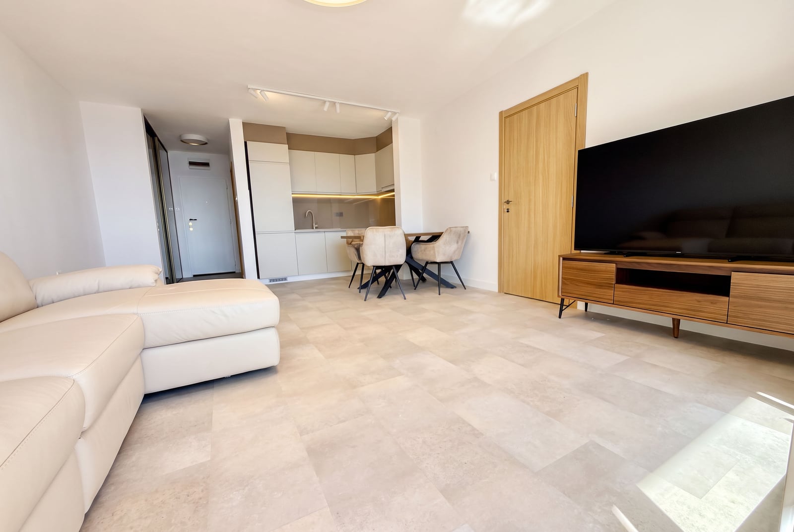 Modern living room with kitchen in an apartment, Sveti Stefan, Montenegro: light furniture, TV area, and dining set.